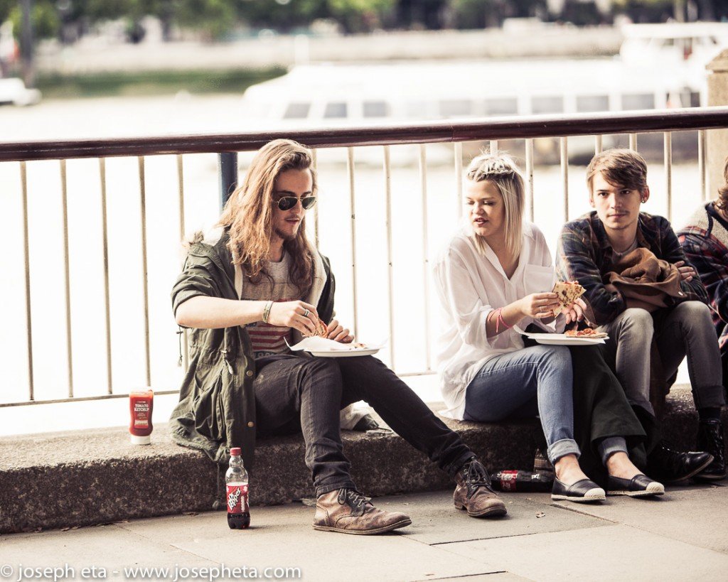 street photography of three friends sharing a pizza at the South Bank in London