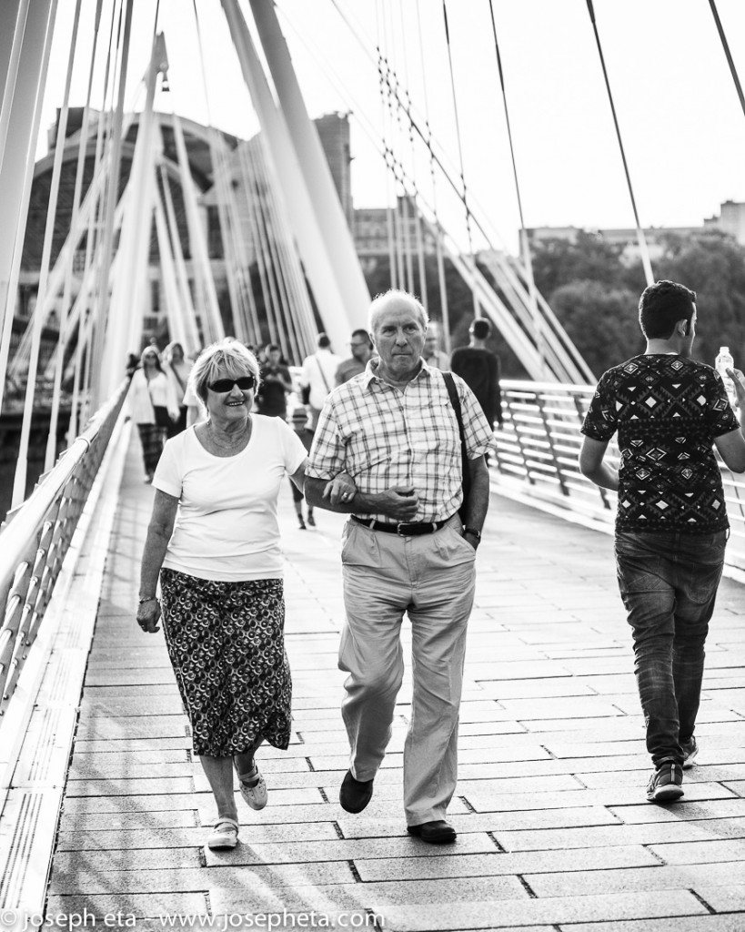 street photography of a mature couple walking on the Hungerford bridge at the South Bank in London