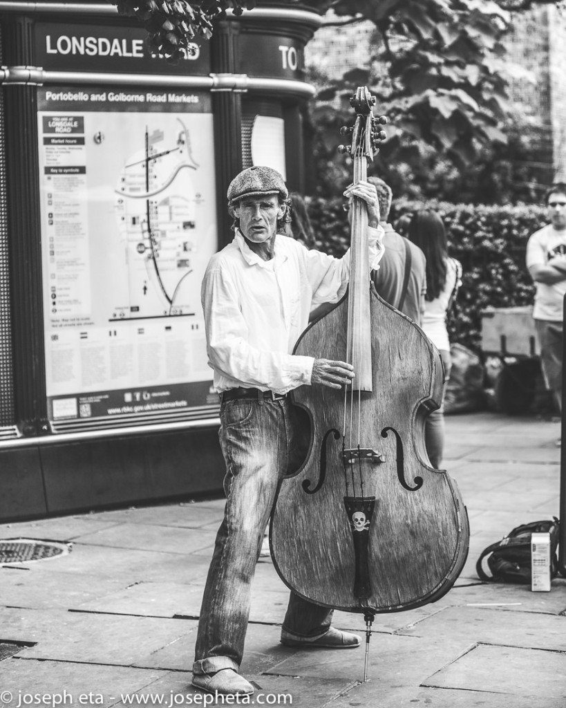 street  photography a street performer playing a bass guitar at portobello road market
