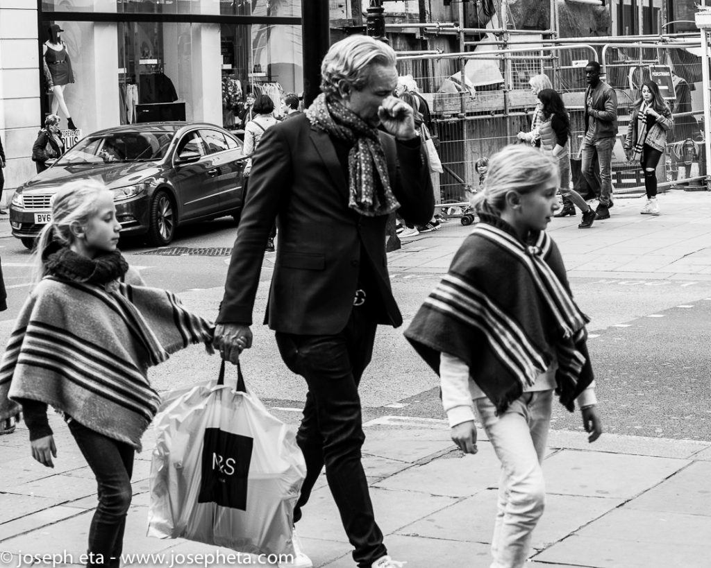 Street photography of a father shopping with his two daughters on Oxford street in London