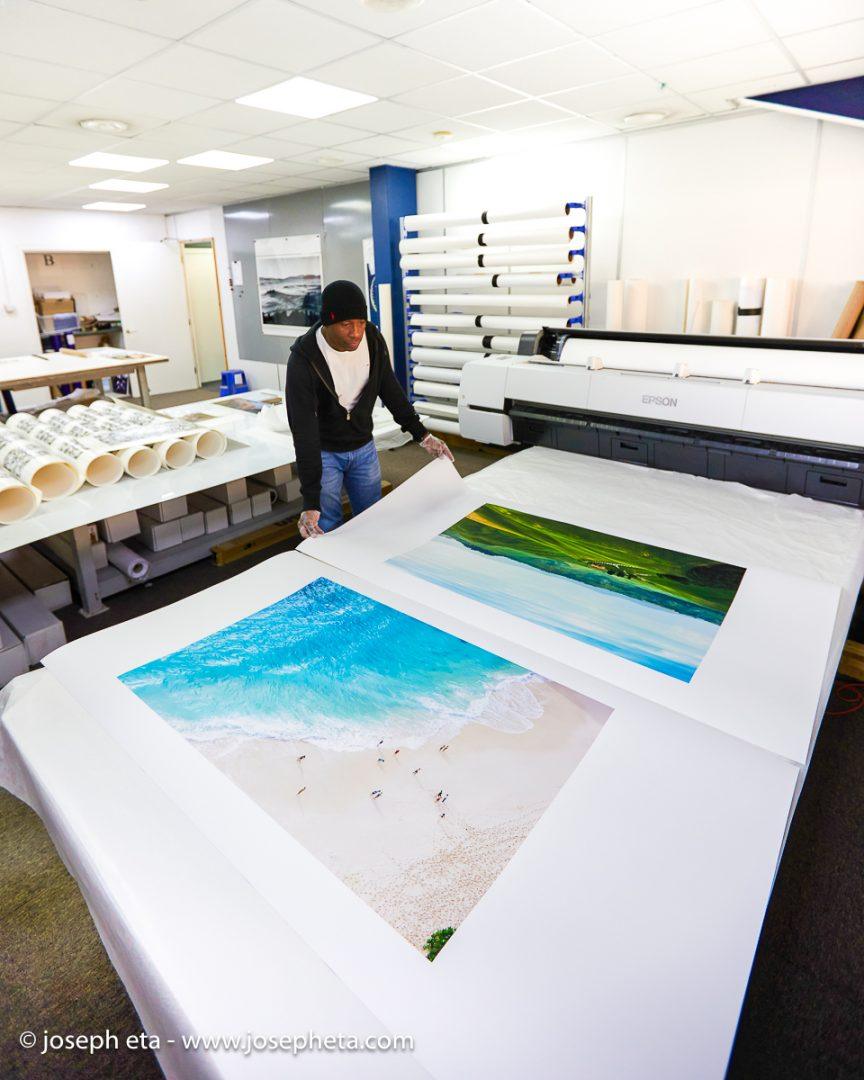 Joseph Eta inspecting a large print of Tuscany and a beach print of Bali