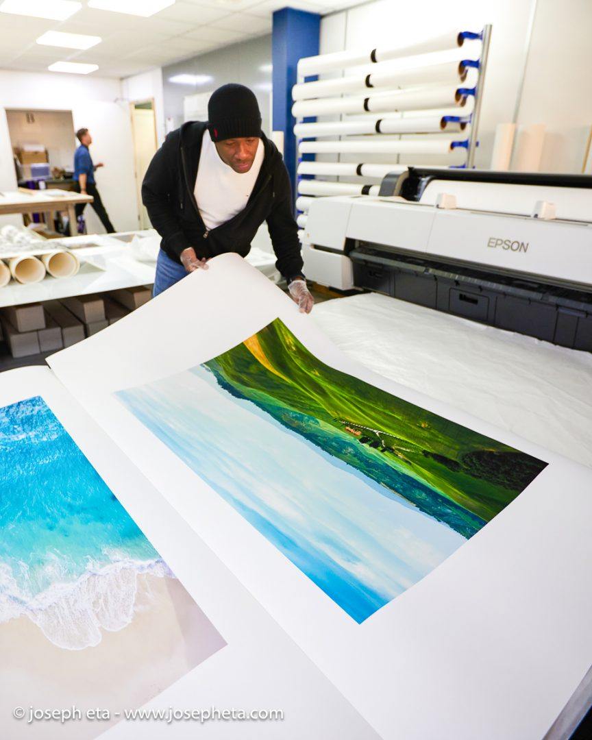 Joseph Eta inspecting a large print of Tuscany and a beach print of Bali
