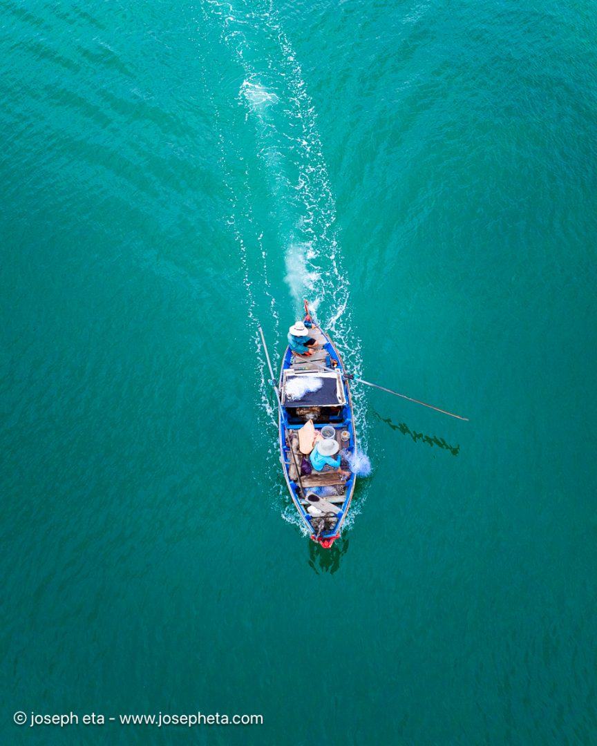 Moody deep blue aerial shot of a boat wake cutting through dark water. A sophisticated, minimalist nautical print with architectural lines, ideal for styling in home offices or libraries.