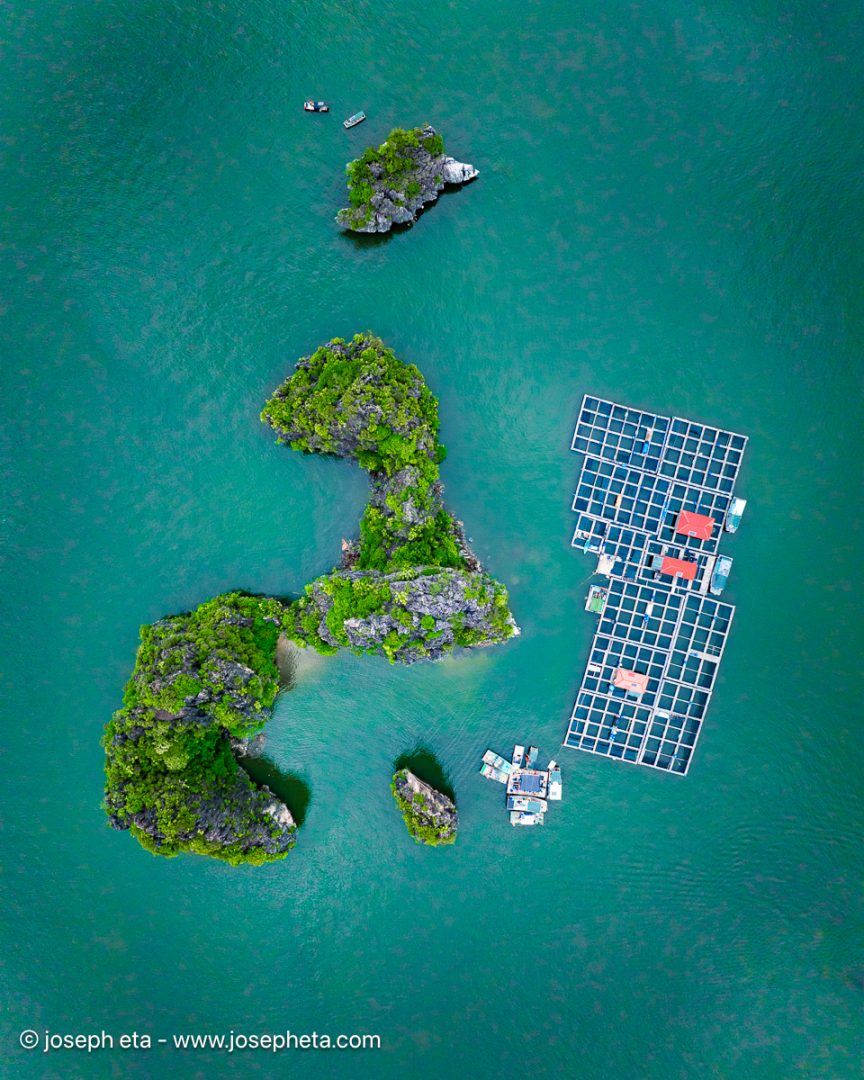High-altitude aerial view of emerald and teal islands scattered in the ocean. Regenerative design-inspired wall art highlighting the organic beauty of nature for social spaces.