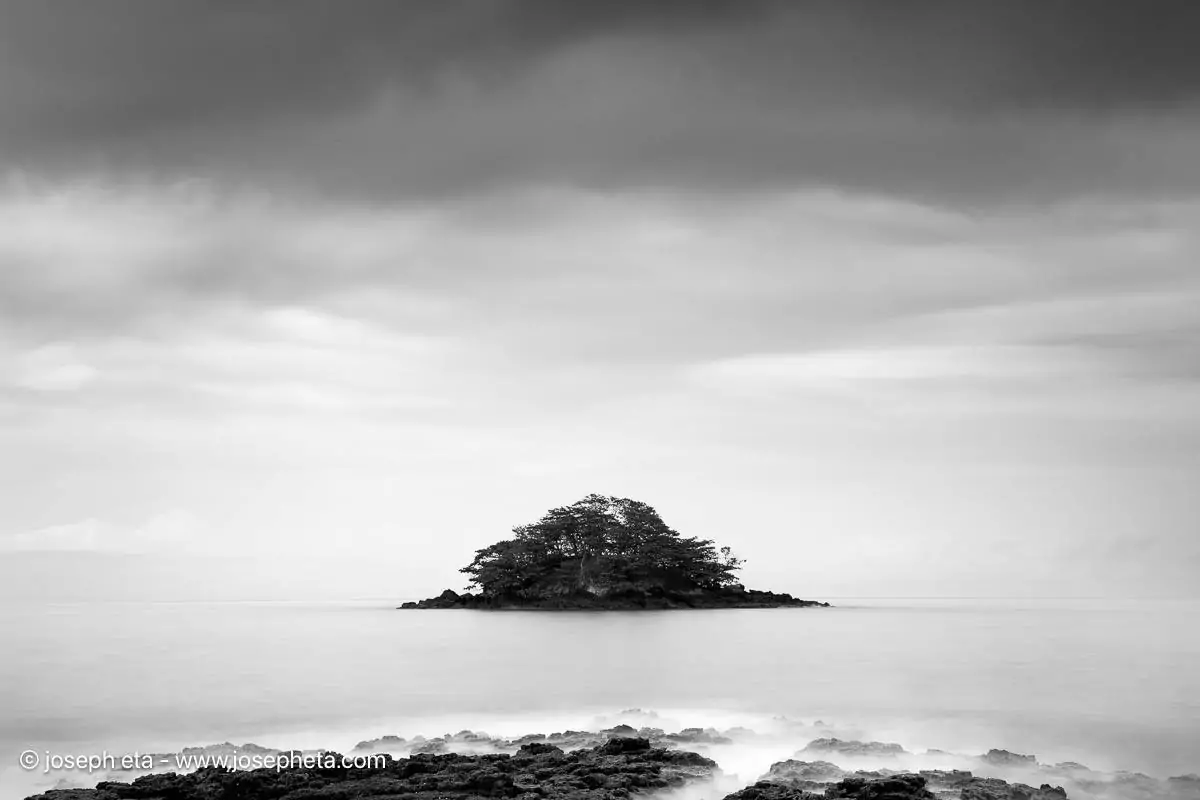 Framed black and white long exposure photography of an island in mist, styled in a dark luxury living room for a visual silence aesthetic.