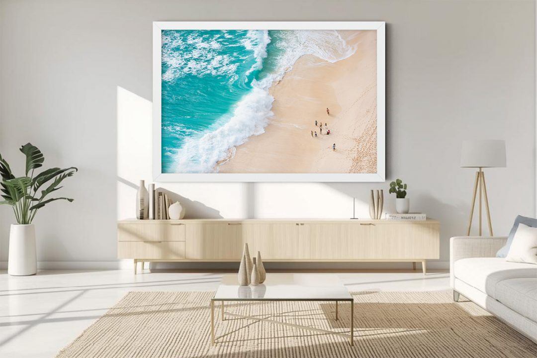 Aerial beach photography showing a diagonal wave wash over pale sand. A balanced composition of turquoise sea and warm sand, perfect for adding visual clarity to narrow hallways or bedrooms.