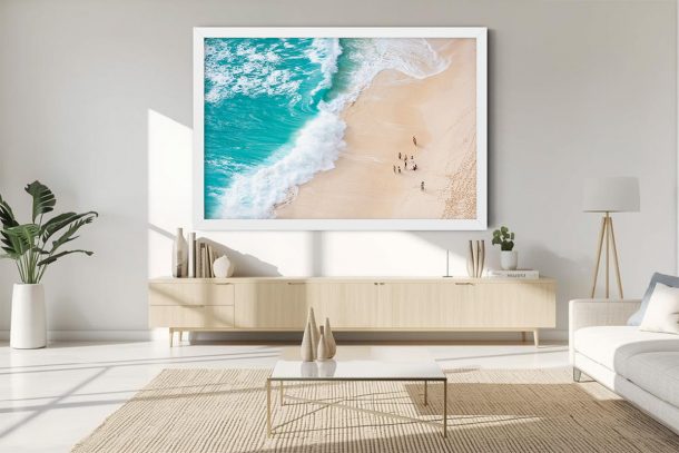 Aerial beach photography showing a diagonal wave wash over pale sand. A balanced composition of turquoise sea and warm sand, perfect for adding visual clarity to narrow hallways or bedrooms.