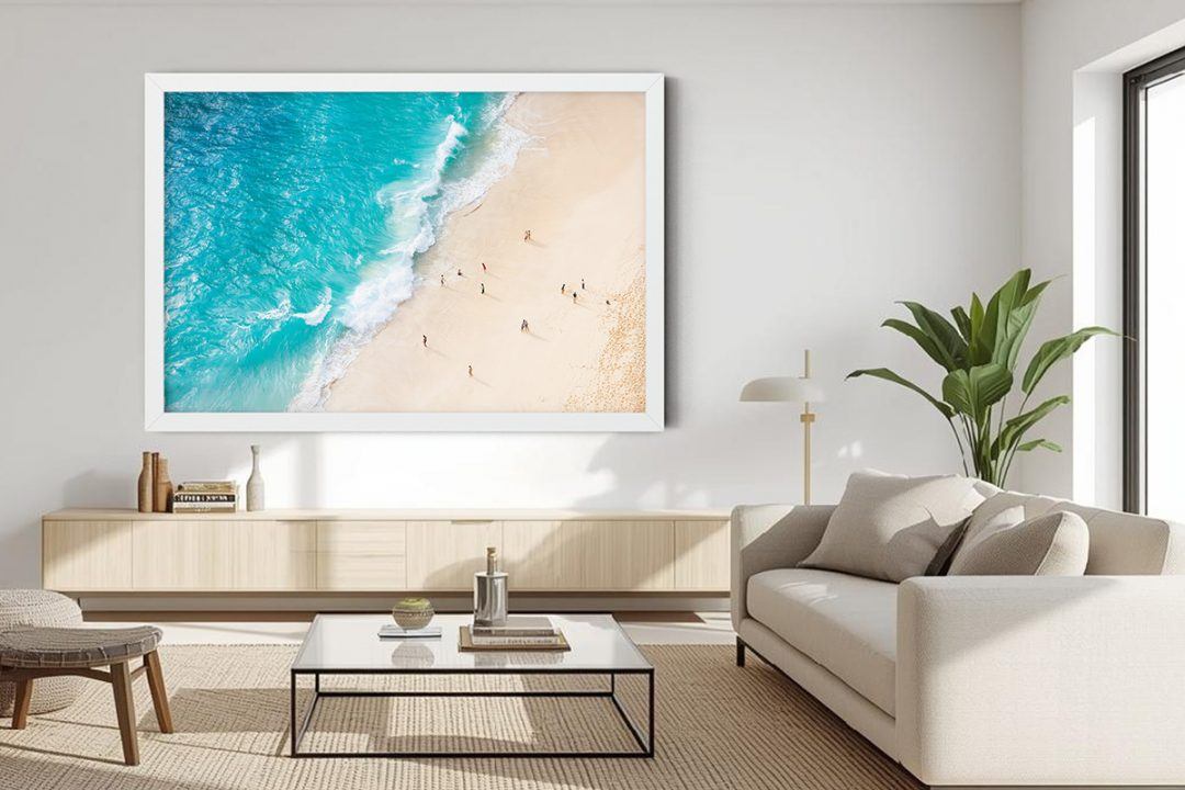 High-key aerial beach photography featuring bright turquoise water, pale white sand, and tiny figures on the shoreline. An optimistic, social art piece representing the 2026 Transformative Teal trend.