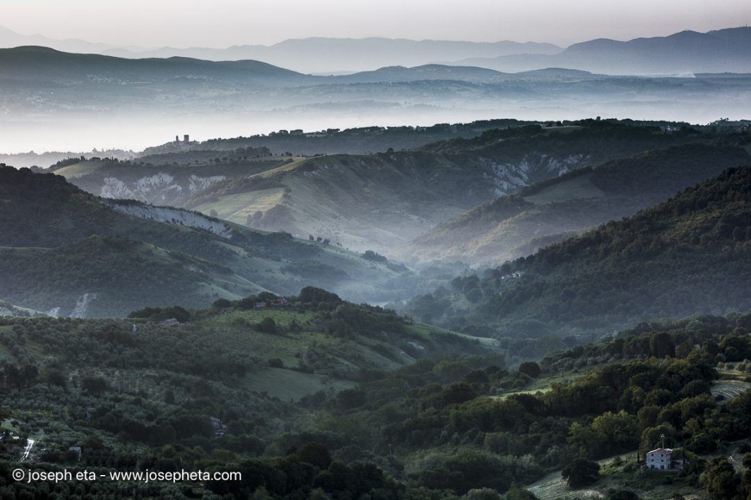 Intertwined rolling hills in early morning mist in Tuscan, Italy