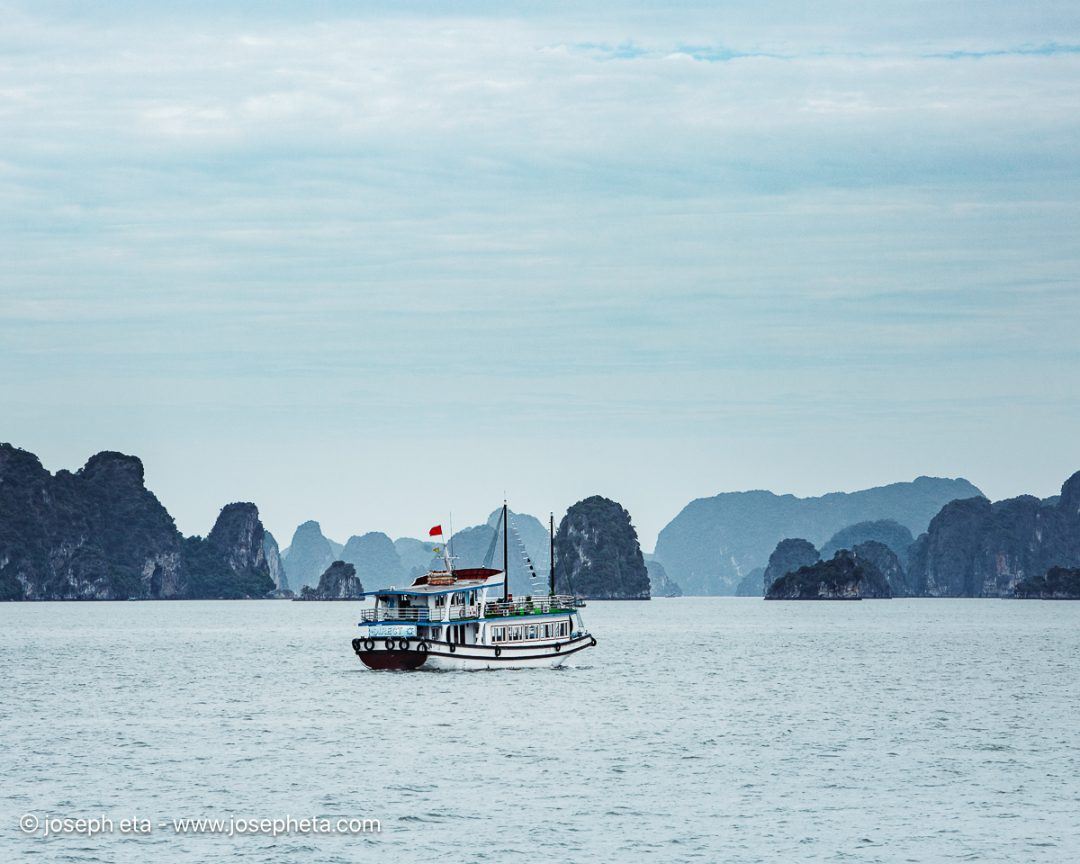 The iconic silhouette of a traditional tour boat sailing through the layered, ancient mountains. This image is curated to evoke a safe, structured exploration, perfectly anchoring a reception area or residential entryway with a sense of refined adventure.