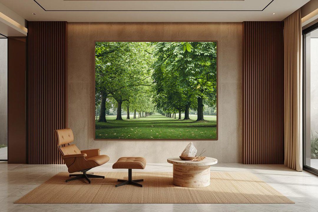 Mockup of biophilic fine art photography featuring a vibrant, lush green tree-lined park, installed in a modern medical lounge area with a tan leather chair, ottoman, and wood-paneled walls.